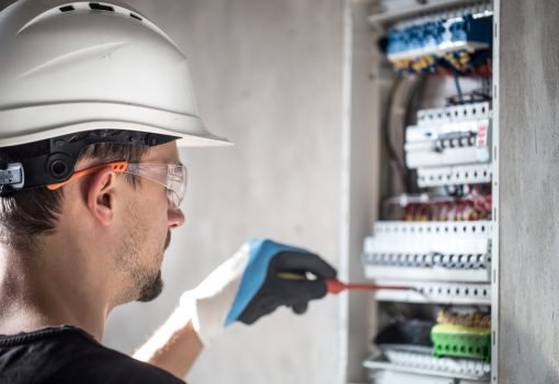 Man, an electrical technician working in a switchboard with fuses. Installation and connection of electrical equipment. Professional with tools in hand. concept of complex work, space for text. SSUCv3H4sIAAAAAAAEAI1Ry2rDMBC8F/oPRucYZMchdv+gh0LvoYe1tIlFFW3QoyWE/HslKyo6ld60M6vZnZ3b81PTsBmcEuyluaUq1krr4LwFr8hEmG8euEUj0dYISuXJKtA1OIMXi4EzRtAErRN8X0nmPPjg0KVhD0iAx1PUyOCvRN7okOumECsZf0SKvSNdNLJNxbgwJ+ZNOYFag0EKjhX+vvlD7NXIZDk5+b9gfnwU33BCI66rtcqyRY2QLR9yK/v89mjP9REgSEWV/y8SoFPDtlK6WCWUOVXfyC9rHuWboGC8TSuwYoNpogvMOoVxjJpY8AWci+2y4NUgEU9B52qOIb8aeKgyGTNLZbftu3EYdkPX7Uc+8h1nJWcSn0rWFnP0i4qUvVa4ShuwnostiGnfTv00tEOPuxYQx3bY81FwfpxG4PHw9x+hX0Y7sQIAAA==